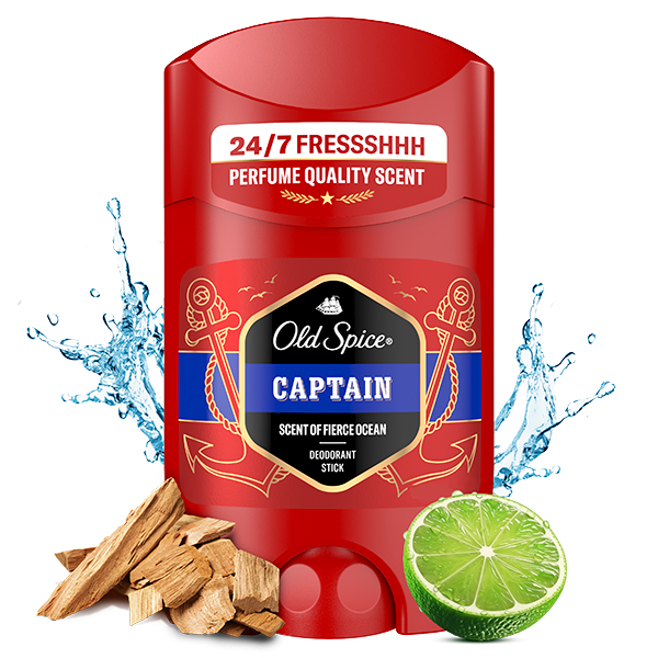 Old Spice Captain deodorant stick in red packaging labeled ‘24/7 Fresh,’ with water splashes, lime, and wood pieces around it to suggest fragrance notes.